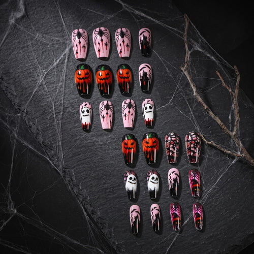 Long pink and black Halloween press-on nails laid out on dark stone