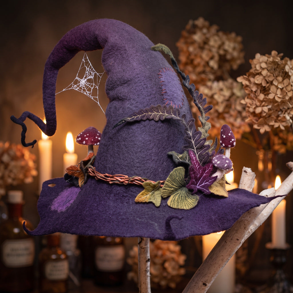 Felted wool witch hat resting on a wooden stand by candlelight