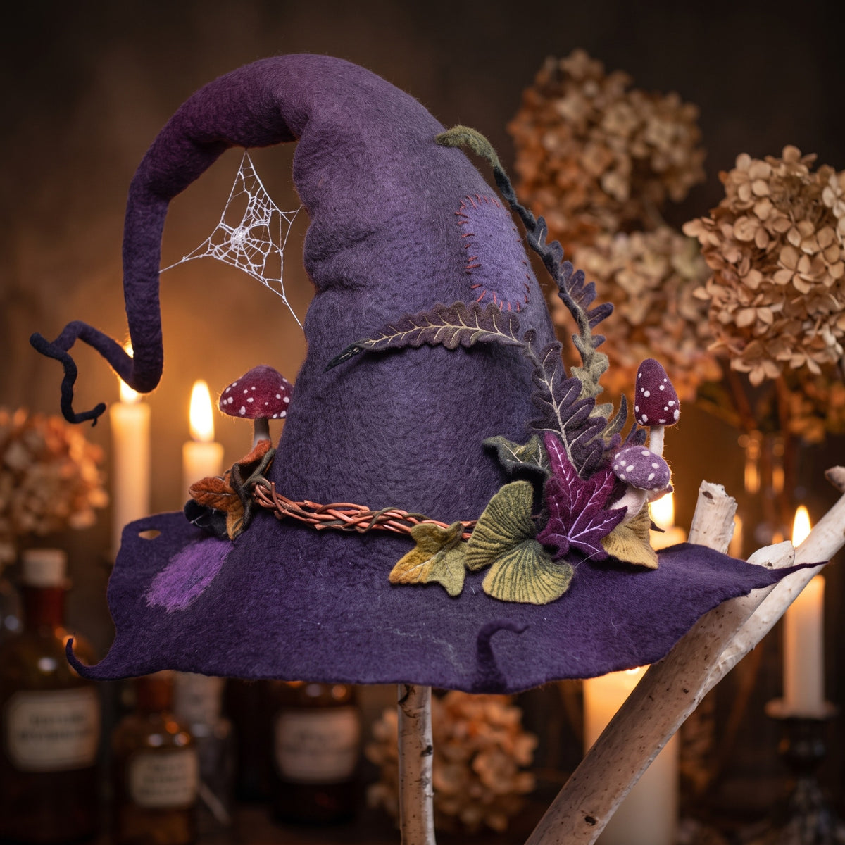 Felted wool witch hat resting on a wooden stand by candlelight