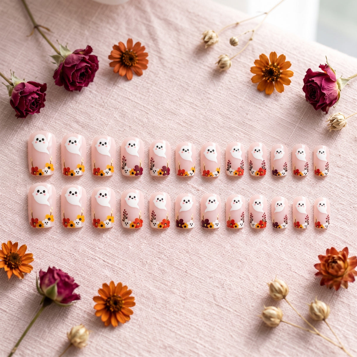 Soft pink press-on nails with ghost and flower artwork on pink linen