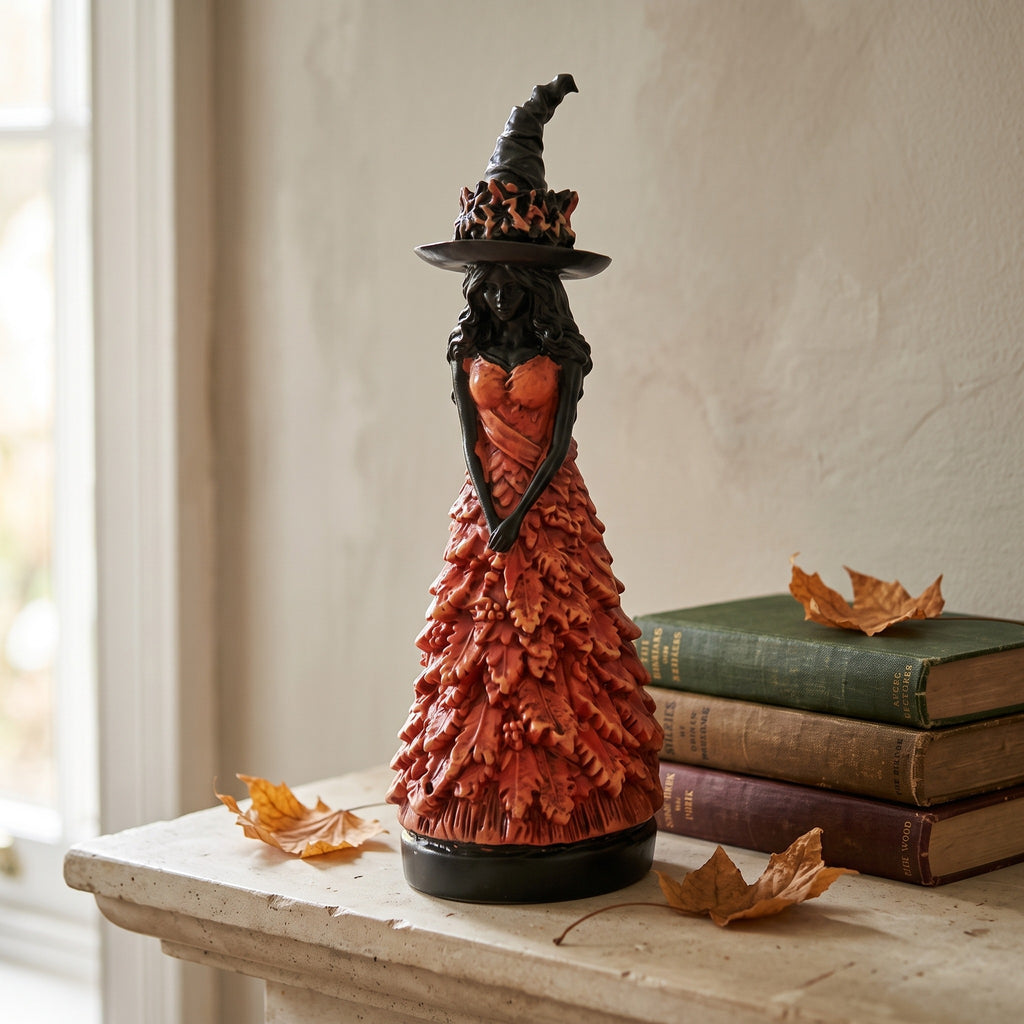 Resin witch figurine with an autumn leaf gown standing on a stone mantel