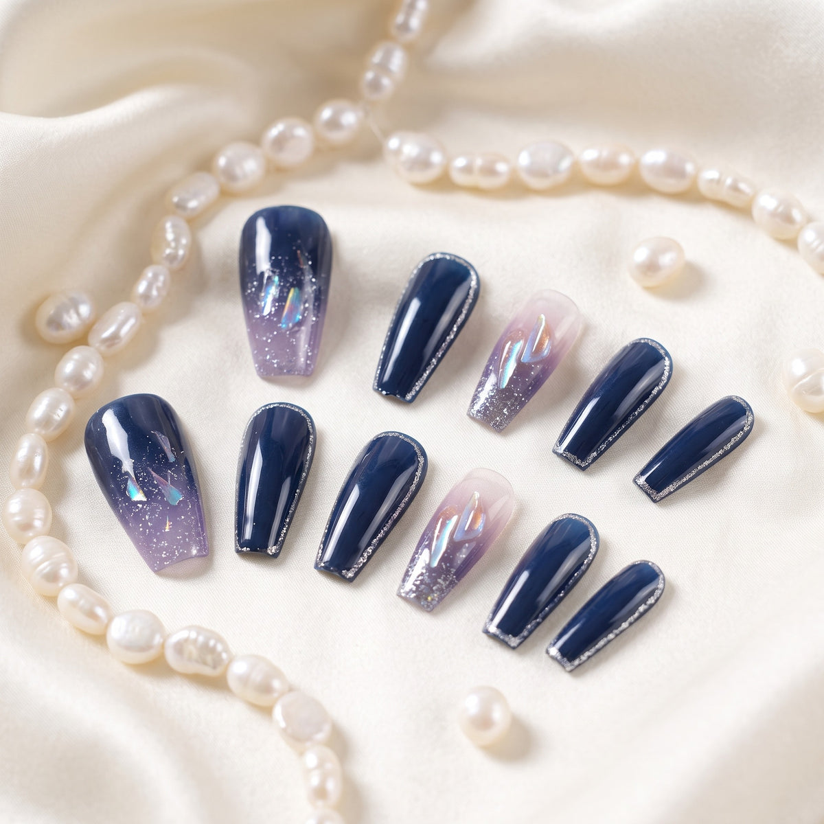 Navy blue press-on nails with silver glitter accents on ivory silk